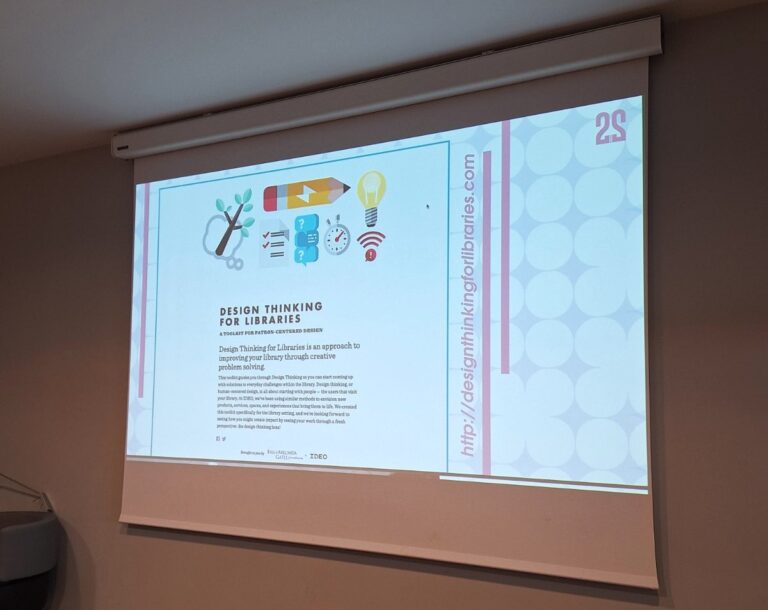 Projektor, ki projecira powerpoint za delavnico Design thinking ofr libraries. slika prikazuje platno, kjer je opis oblikovalskega razmišljanja.